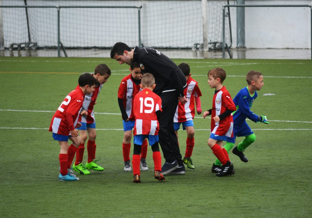 A sports coach with youth players on a soccer field
